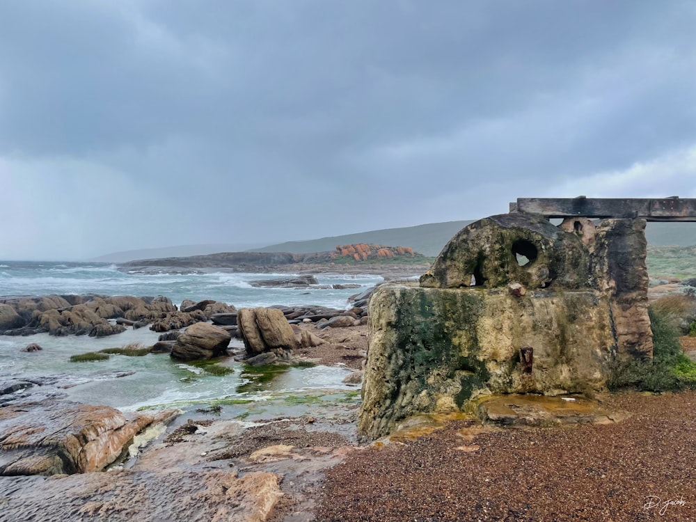 a stone structure sitting on top of a beach next to the ocean