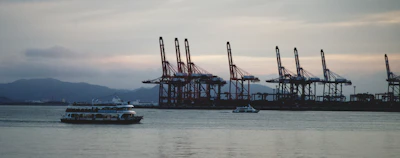 Cargo being loaded onto an offshore supply ship with cranes against a sunset backdrop.