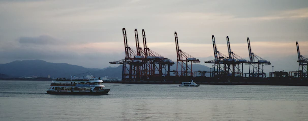 A crane lifting a 40-foot container onto a cargo ship at sunset