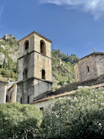 Ancient stone church tower surrounded by lush greenery in the heart of Portet-sur-Garonne.