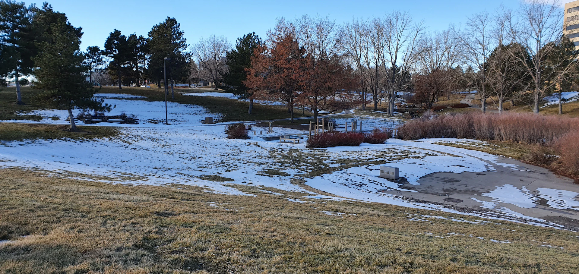 a snow covered field with trees and buildings in the background
