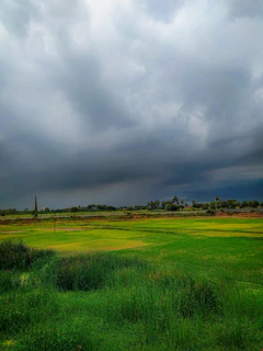 Dark thunderclouds rolling over a green countryside field