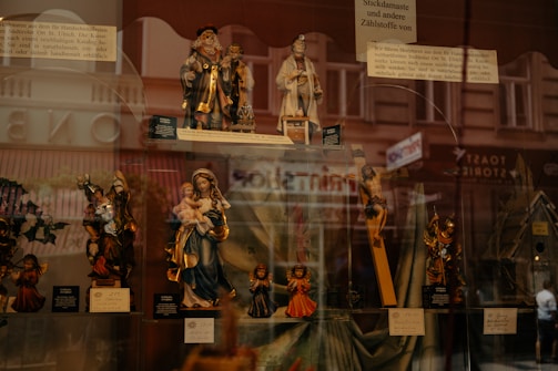 A collection of luminous plexiglass religious figurines displayed on a wooden shelf.