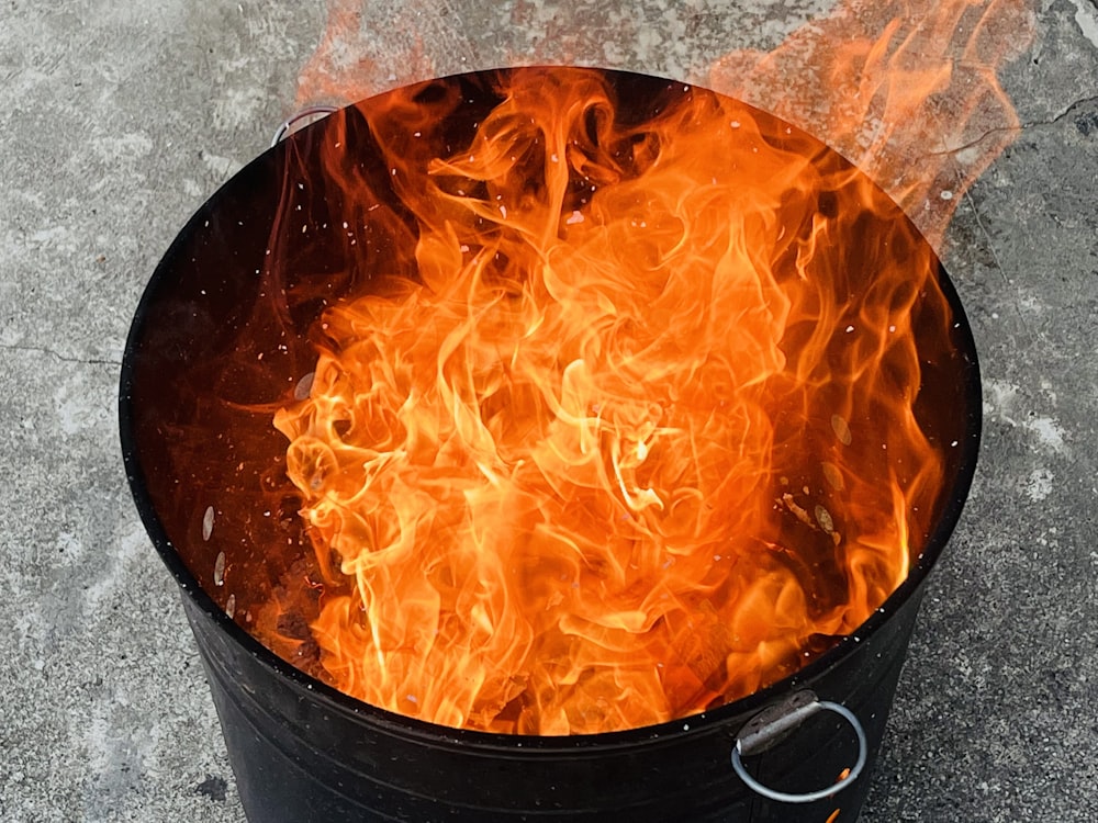 a fire burning inside of a black bucket