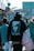 A person wearing a black hoodie with an image of a famous musician and the words 'Until The End of Time' on the back is walking in a busy outdoor urban setting. The street is bustling with multiple people, and there are shops and colorful signs in the background.