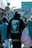 A person wearing a black hoodie with an image of a famous musician and the words 'Until The End of Time' on the back is walking in a busy outdoor urban setting. The street is bustling with multiple people, and there are shops and colorful signs in the background.