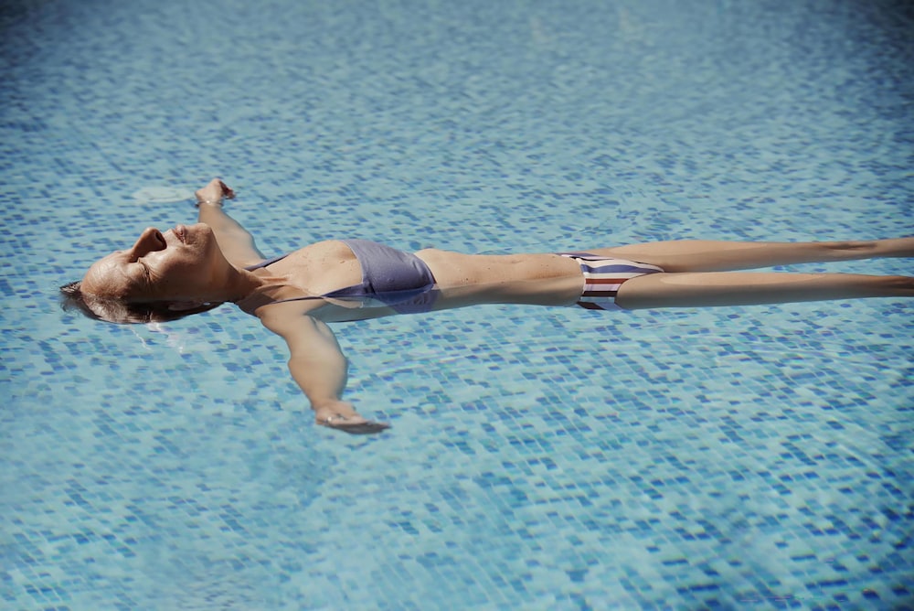 a woman in a bikini swimming in a pool