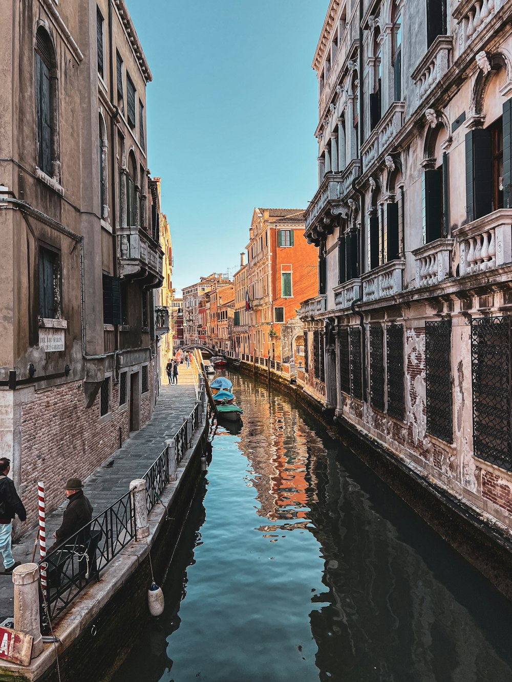 a man sitting on a bench next to a canal