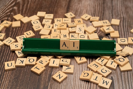 Close-up of hands arranging wooden letter tiles on a rustic table surrounded by autumn leaves.