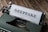 A vintage typewriter with a sheet of paper loaded, displaying the word 'DEEPFAKE' in bold letters. The typewriter sits on a wooden surface, adding a rustic touch to the image.