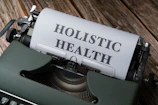 a close up of a typewriter with a paper that says holstic health