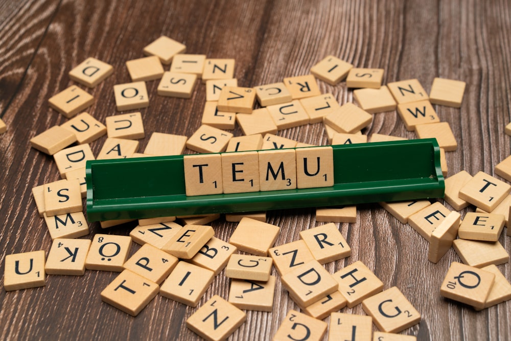 scrabble tiles spelling the word temu on a wooden surface