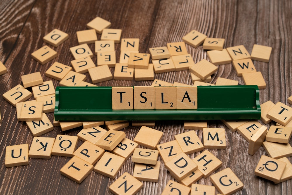 scrabble tiles spelling the word tisla on a wooden table