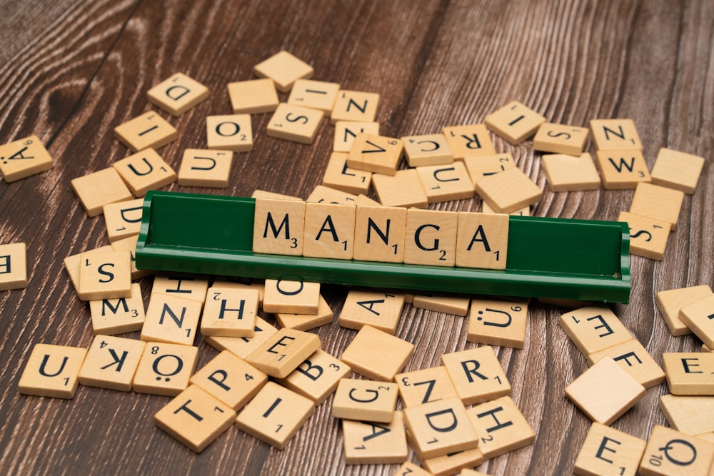 scrabble tiles spelling the word manga on a wooden table