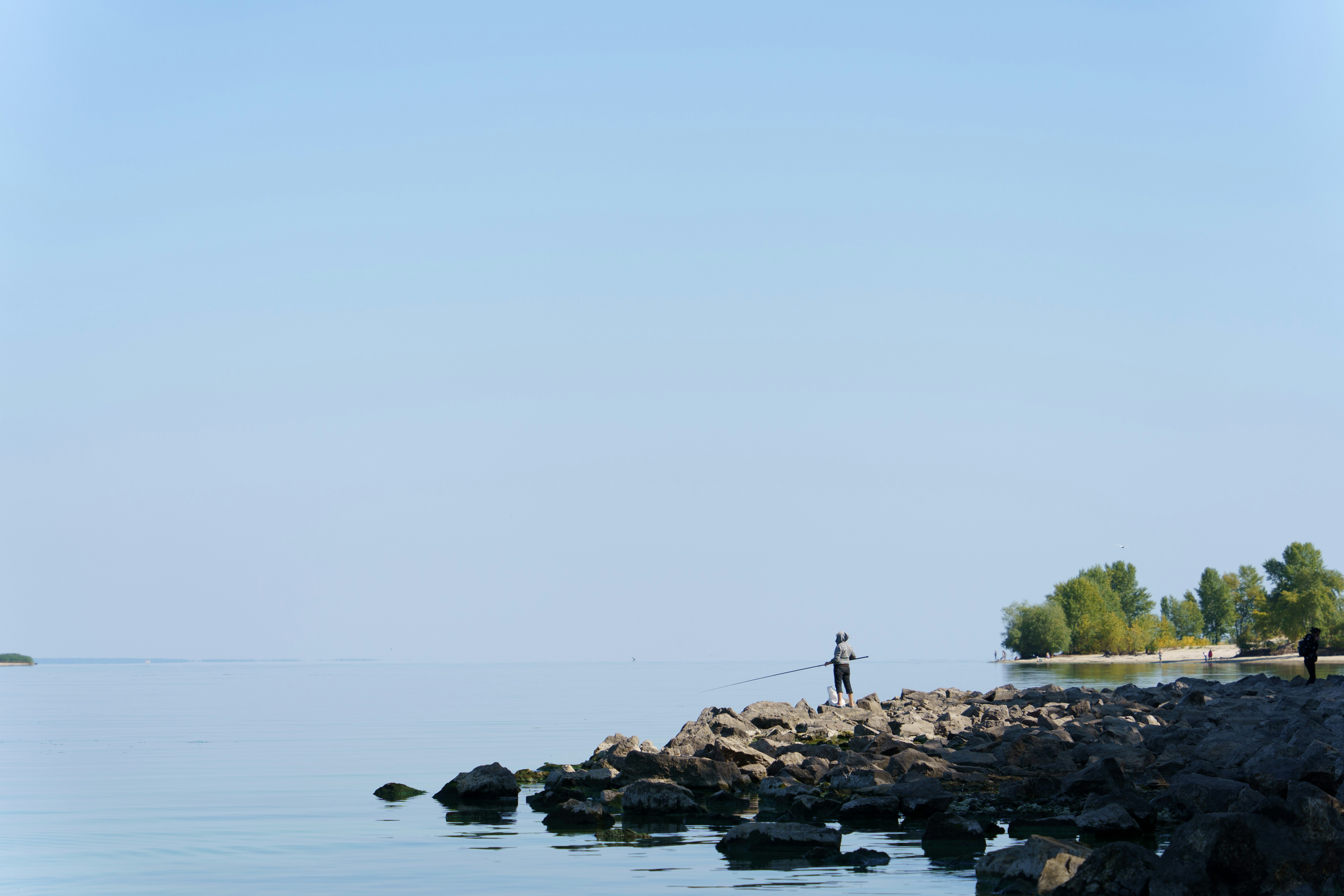 a person flying a kite on a rocky shore