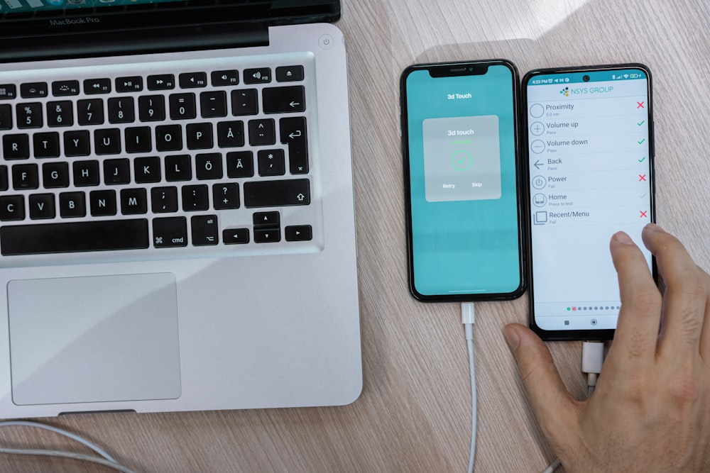 a person holding a cell phone next to a laptop