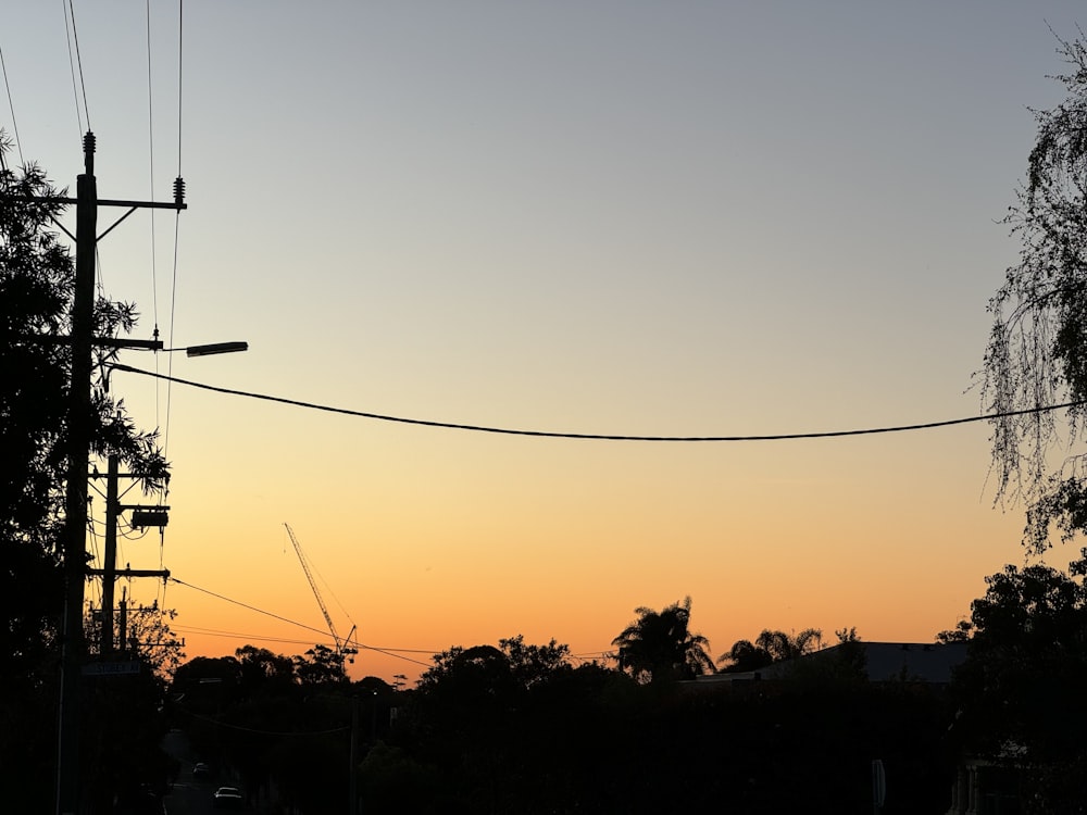 the sun is setting behind a telephone pole