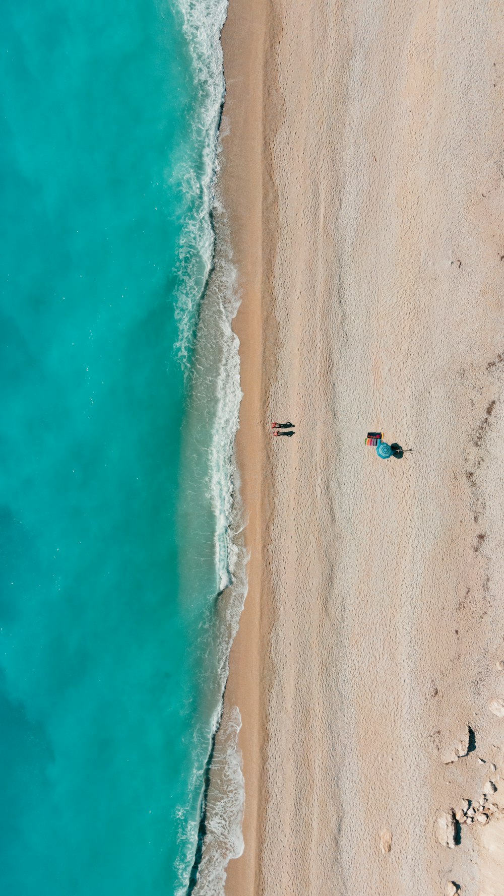 an aerial view of two people laying on the beach