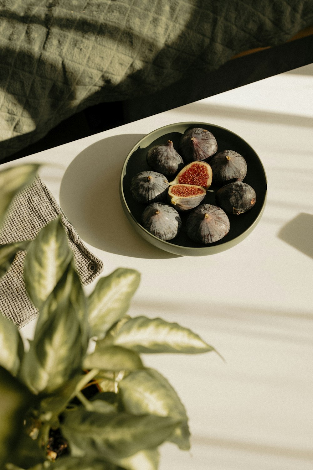 a plate of figs on a table next to a potted plant