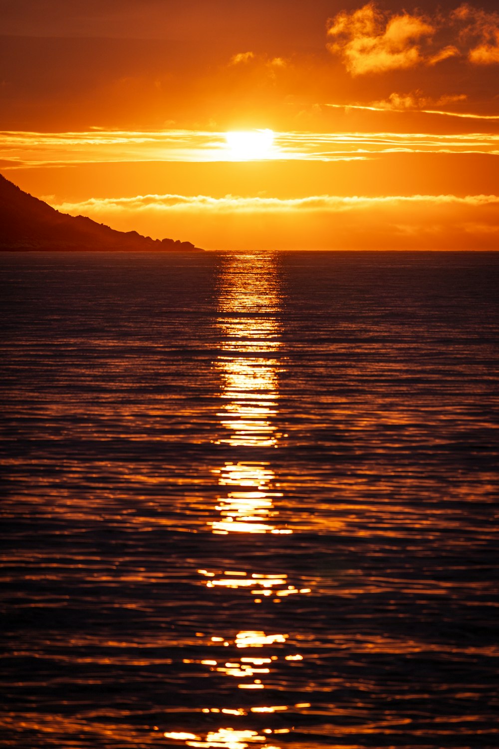 una gran masa de agua con una puesta de sol en el fondo