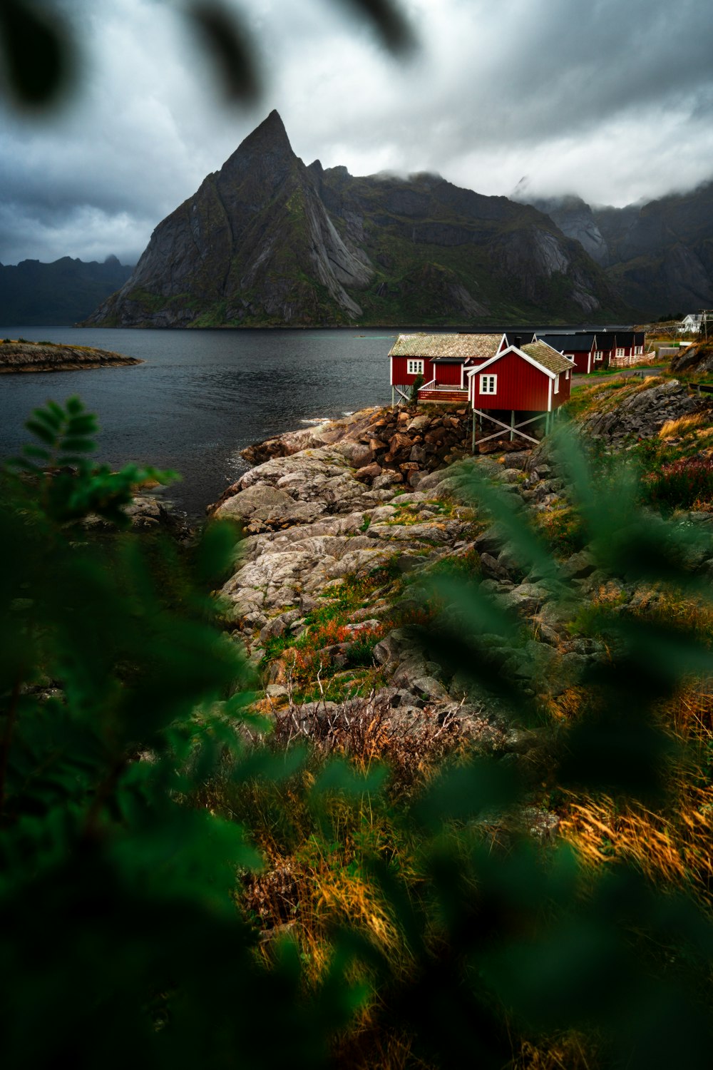 a red house sitting on top of a lush green hillside