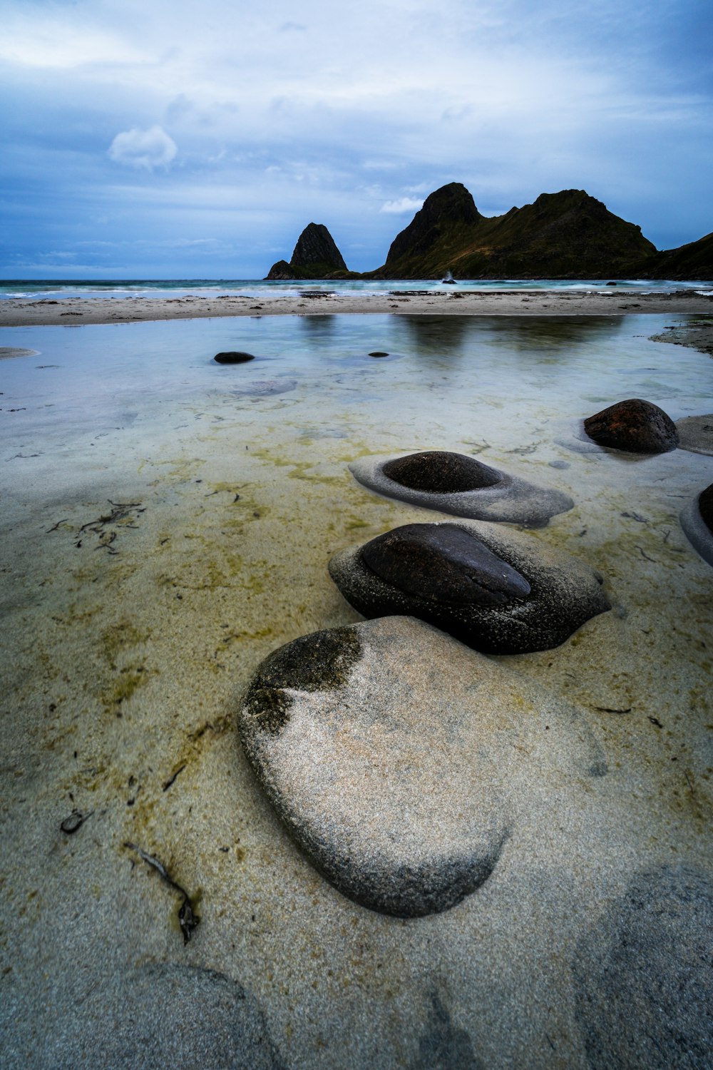 a group of rocks sitting on top of a sandy beach