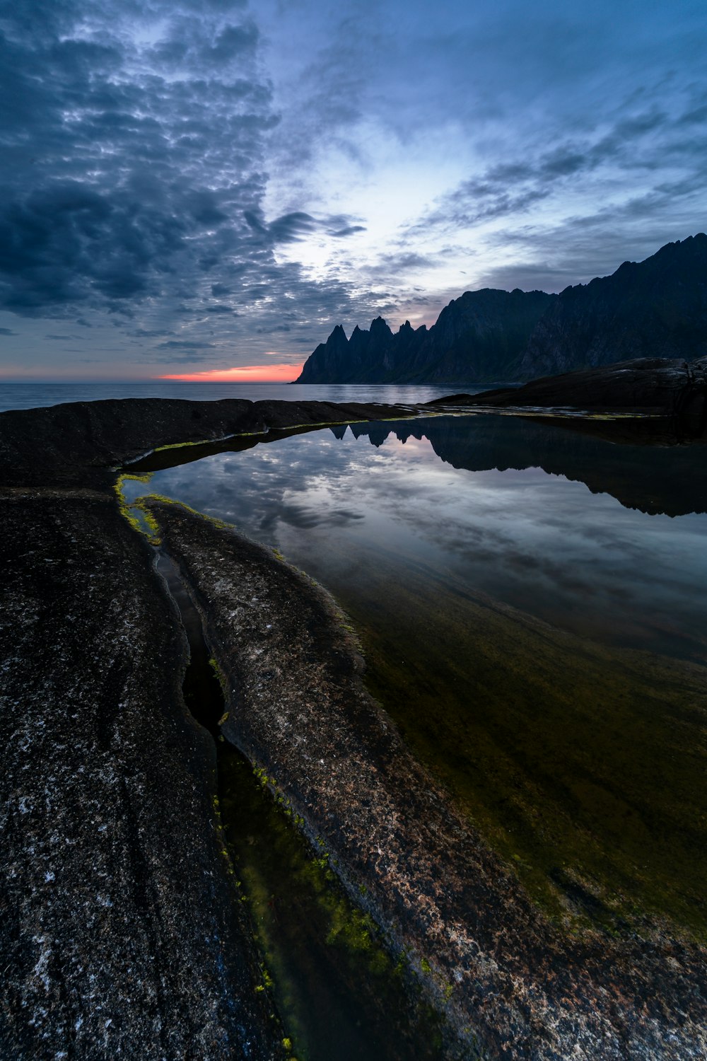 Un cuerpo de agua rodeado de montañas bajo un cielo nublado