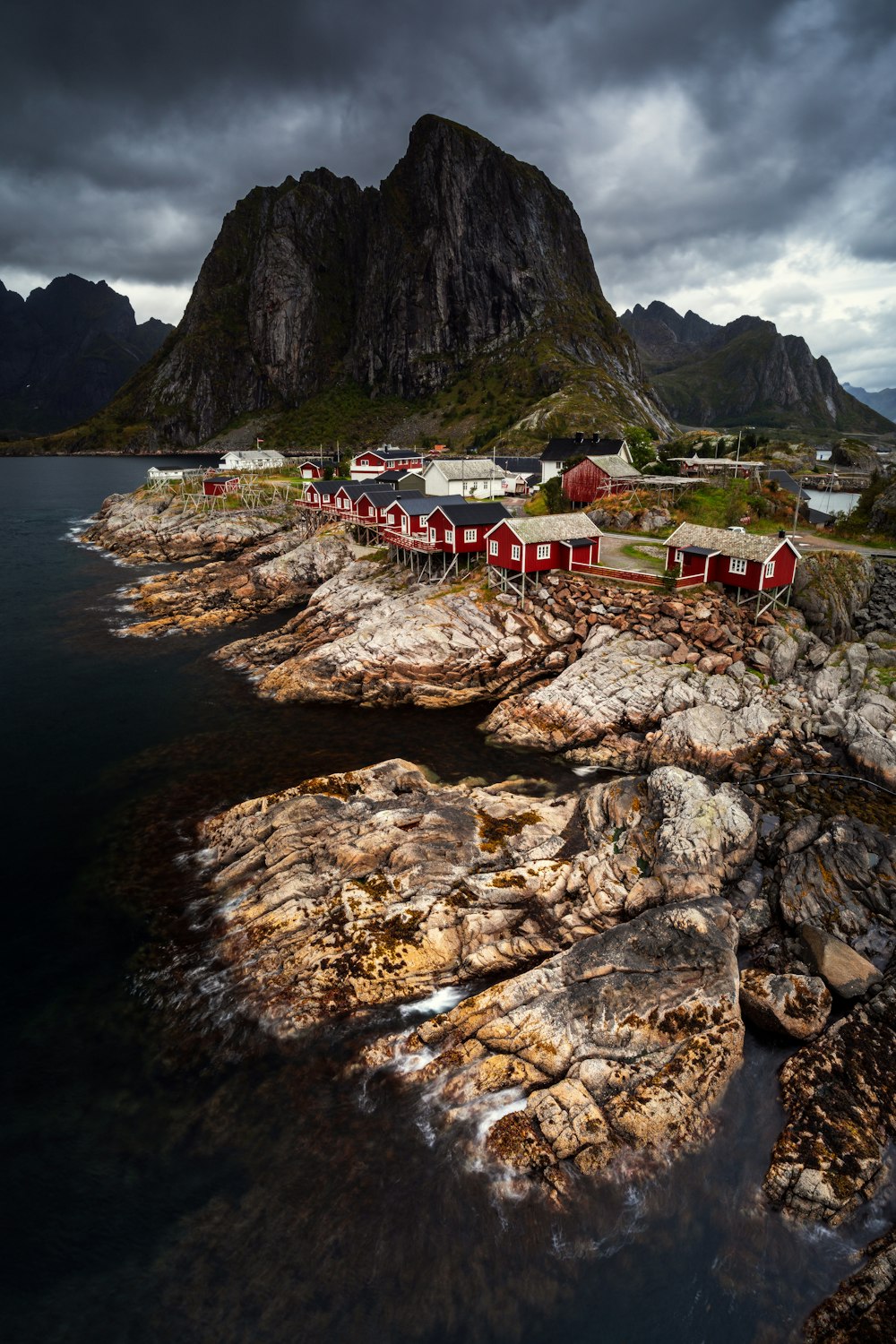 a red house sitting on top of a rocky shore