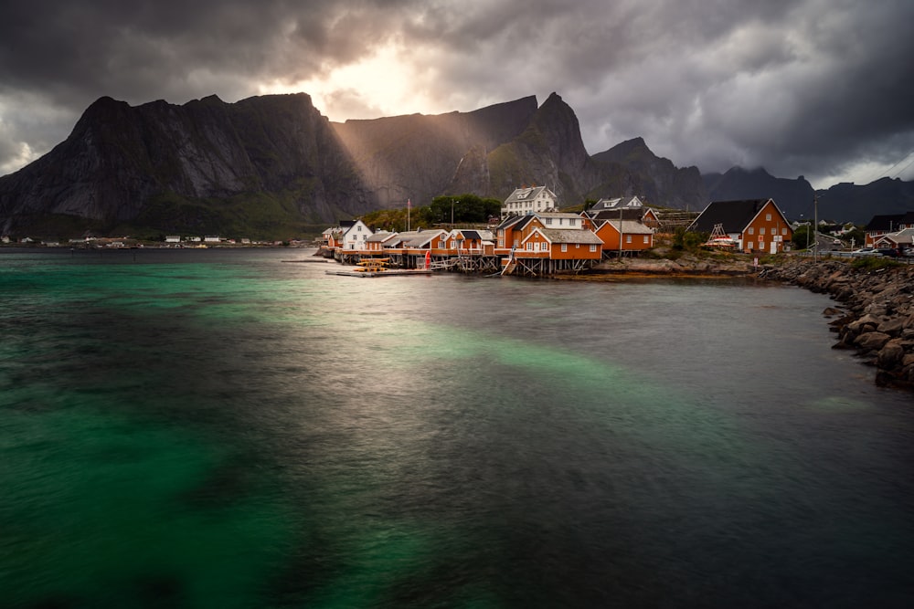 a body of water with houses and mountains in the background