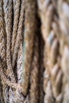 Close-up of several thick, textured ropes arranged in a vertical fashion, showing detailed fibers and intertwined strands.