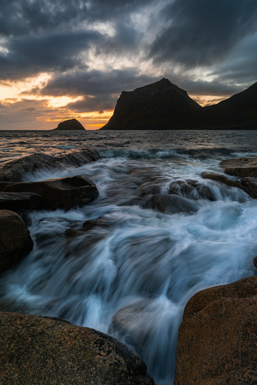 a body of water surrounded by rocks under a cloudy sky