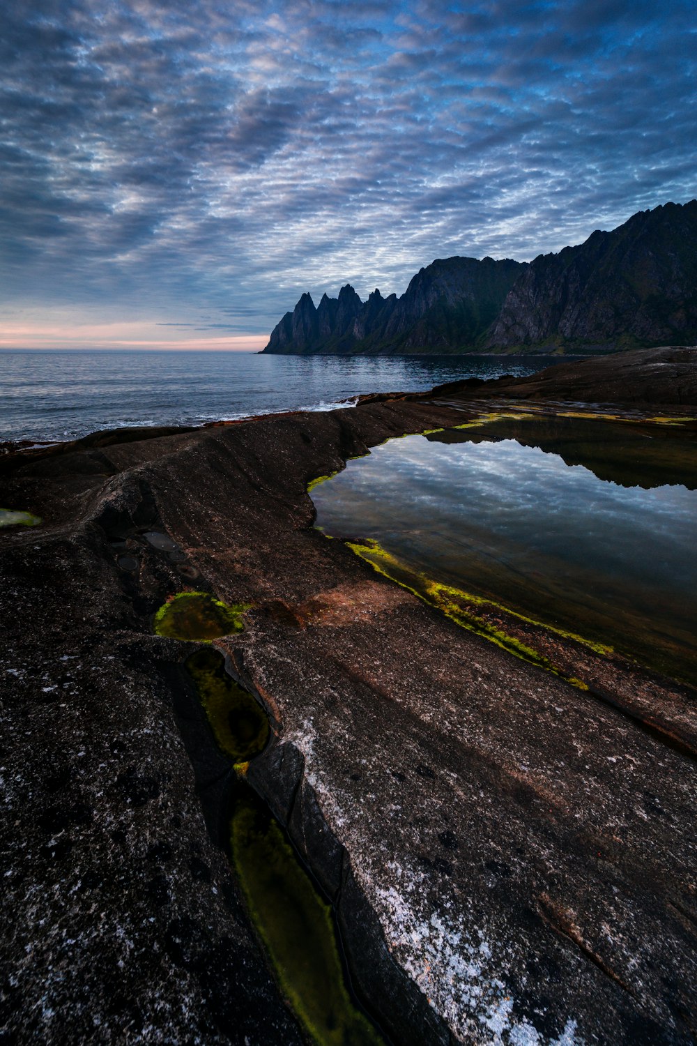 a large body of water sitting next to a rocky shore