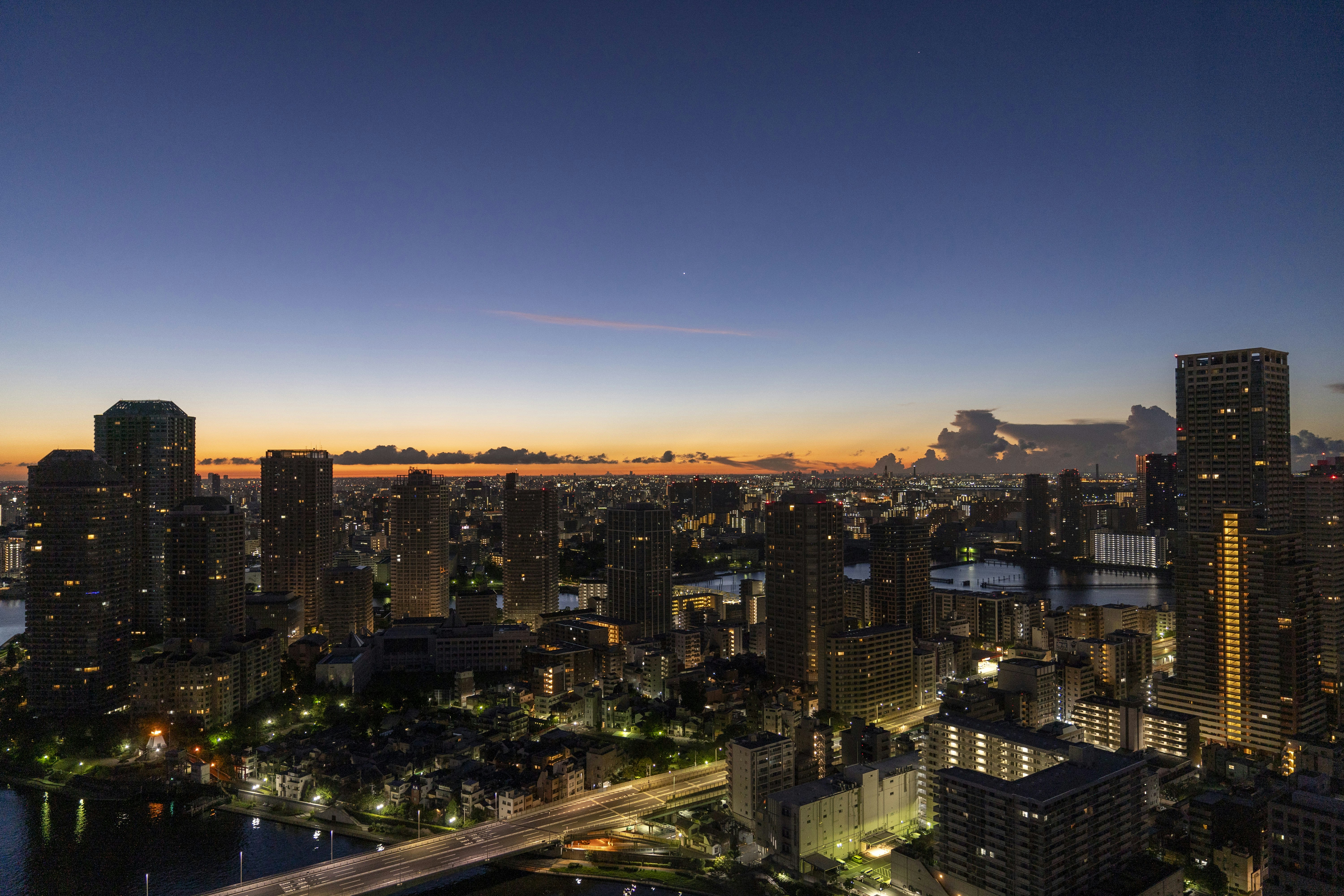 a view of a city at night from the top of a building, Sunrise over Tokyo.