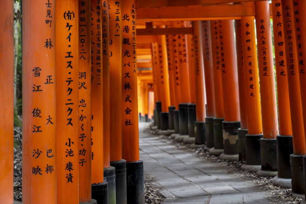 a row of orange pillars with asian writing on them