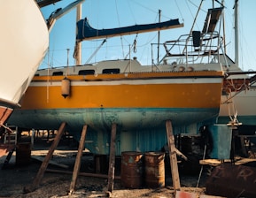 a yellow and white boat sitting on top of a beach
