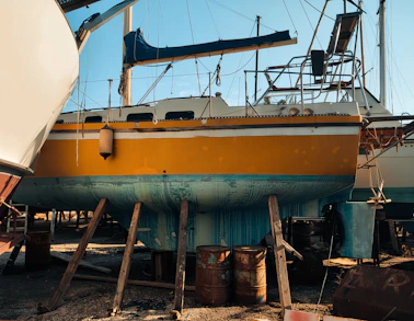 Johan Dubbelman inspecting a yacht hull in a bright shipyard under a clear blue sky.