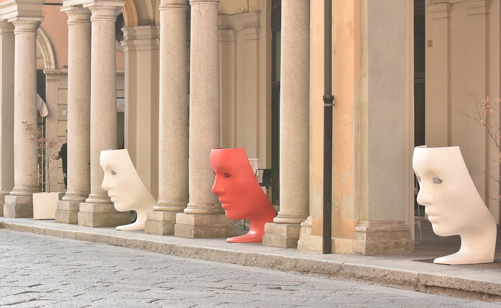 a row of mannequin heads sitting on the side of a building