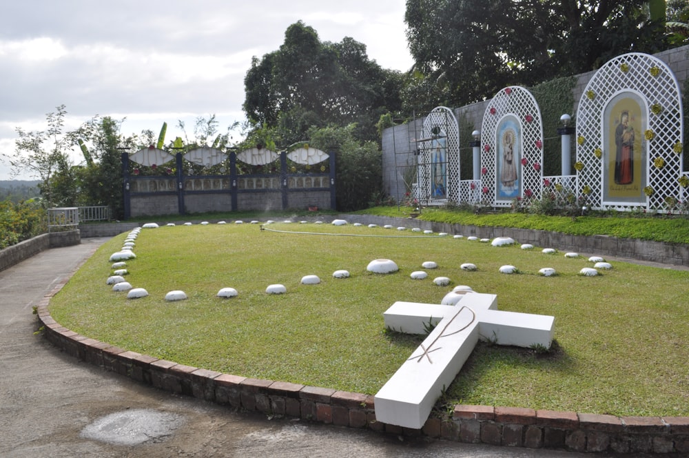 a white cross sitting on top of a lush green field