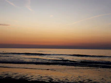 the sun is setting over the water at the beach