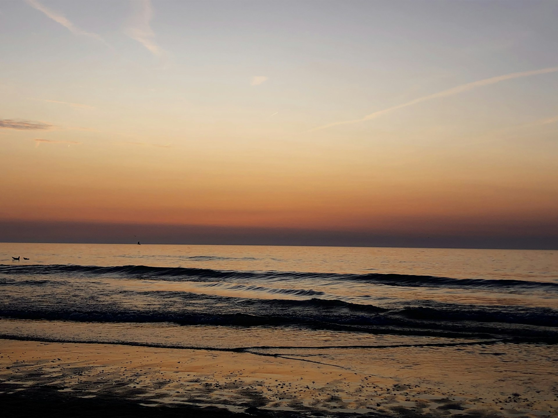 the sun is setting over the water at the beach