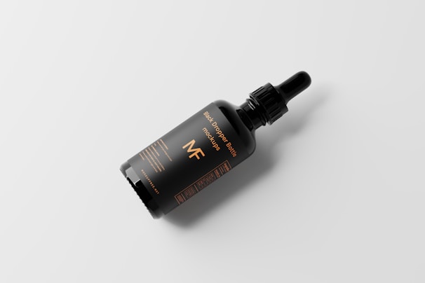A sleek black and deep orange supplement bottle resting on a smooth stone surface.