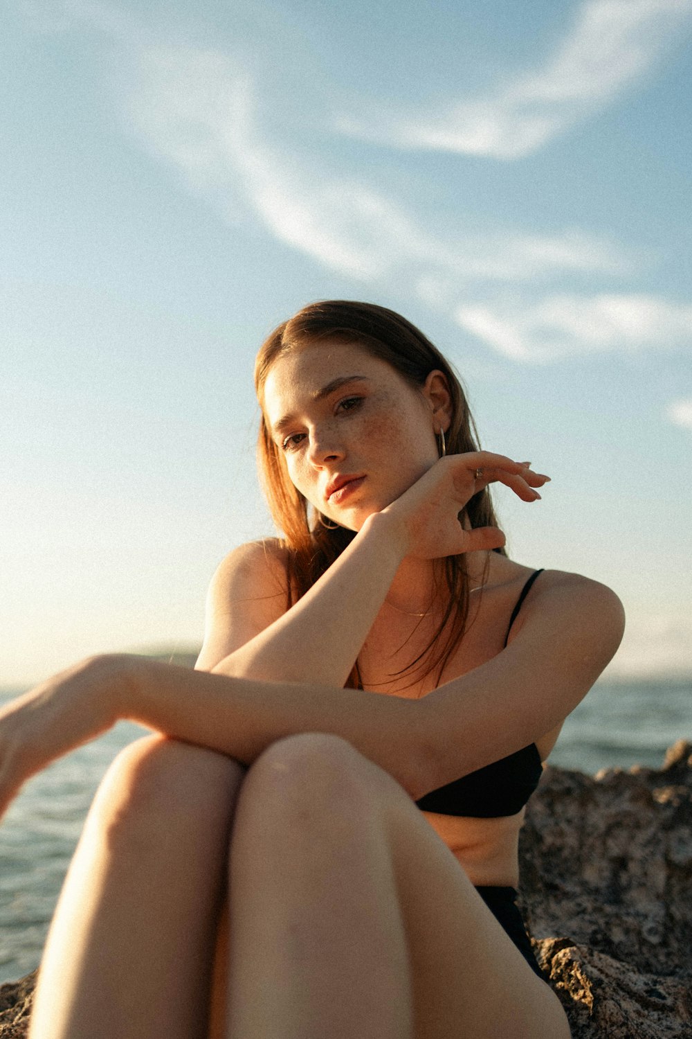 a woman sitting on a rock next to the ocean