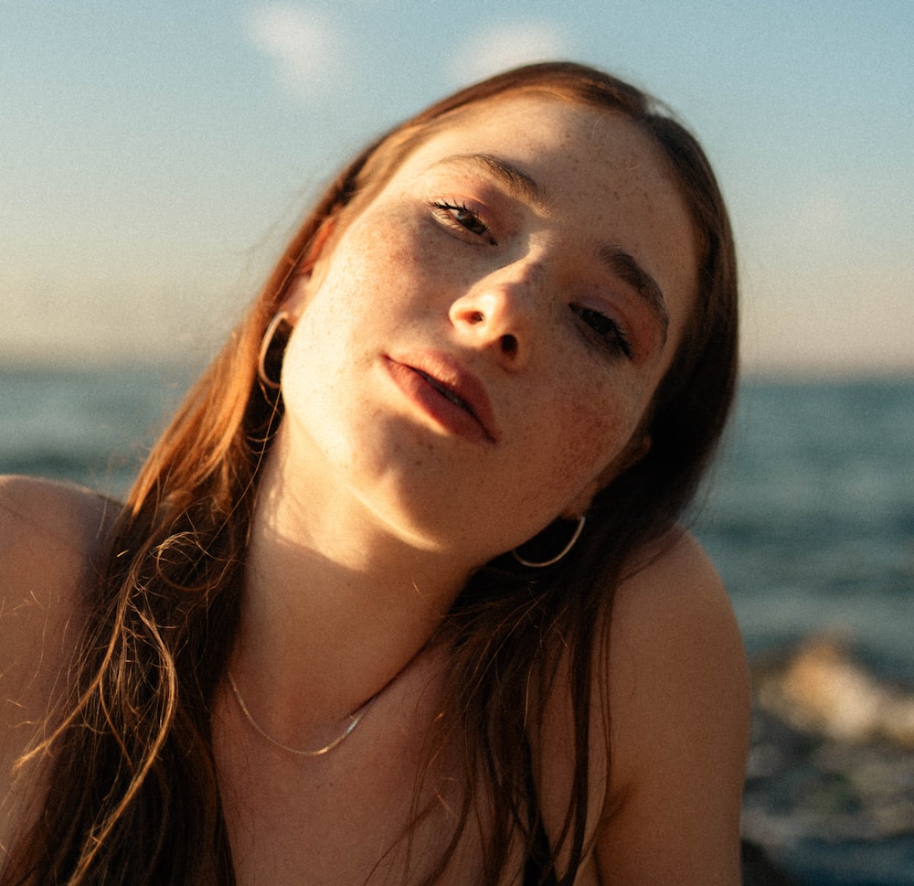 a woman sitting on a beach next to the ocean