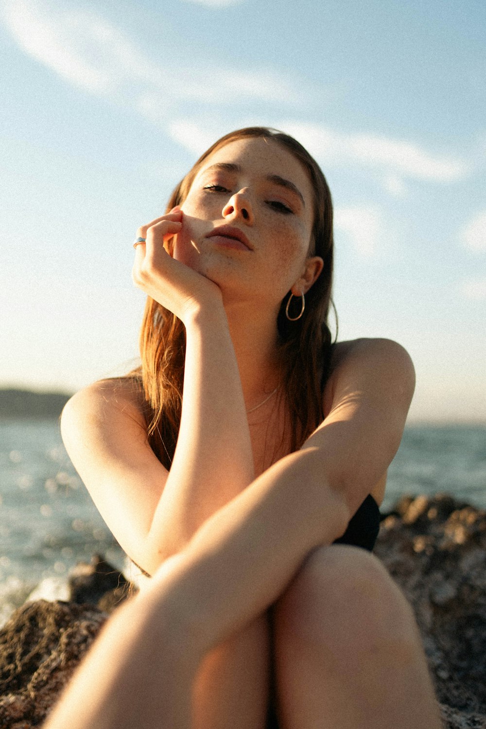 a woman sitting on a rock next to the ocean