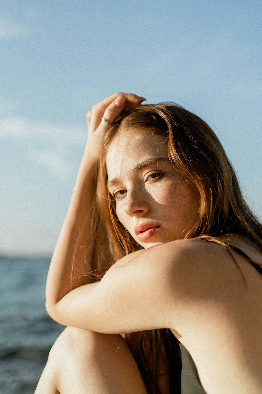 a woman sitting on a beach next to the ocean