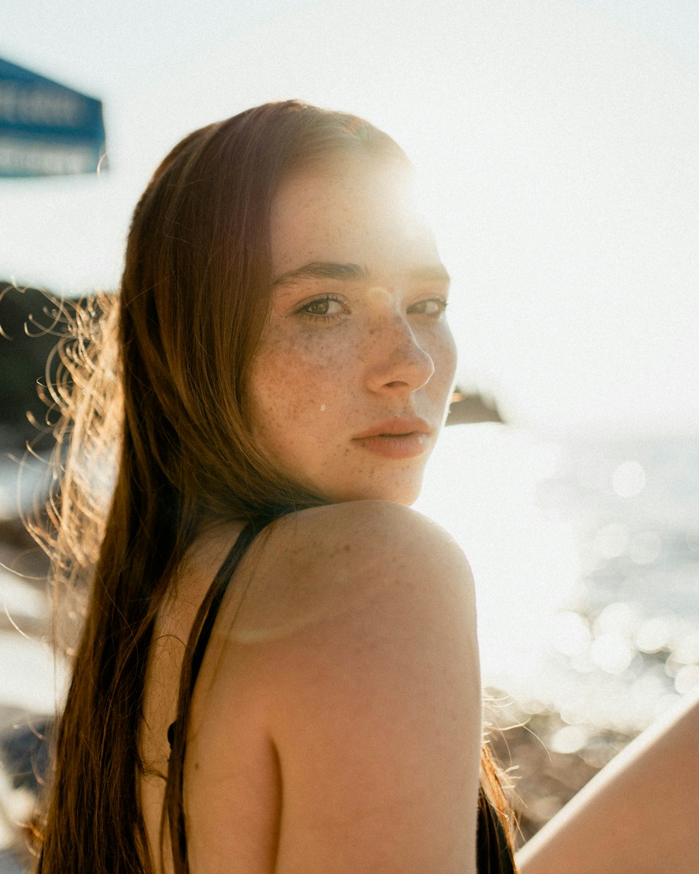 a woman sitting on a beach next to the ocean