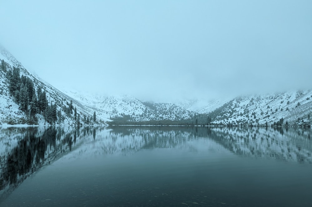 a lake surrounded by mountains covered in snow