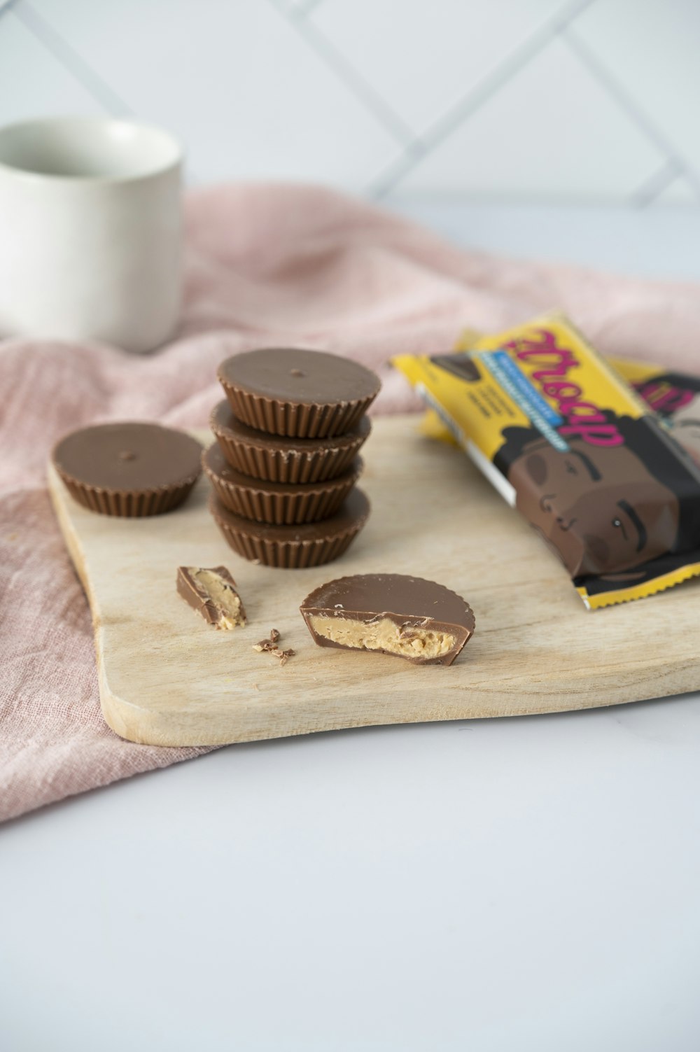 a wooden cutting board topped with chocolates and a cup of coffee