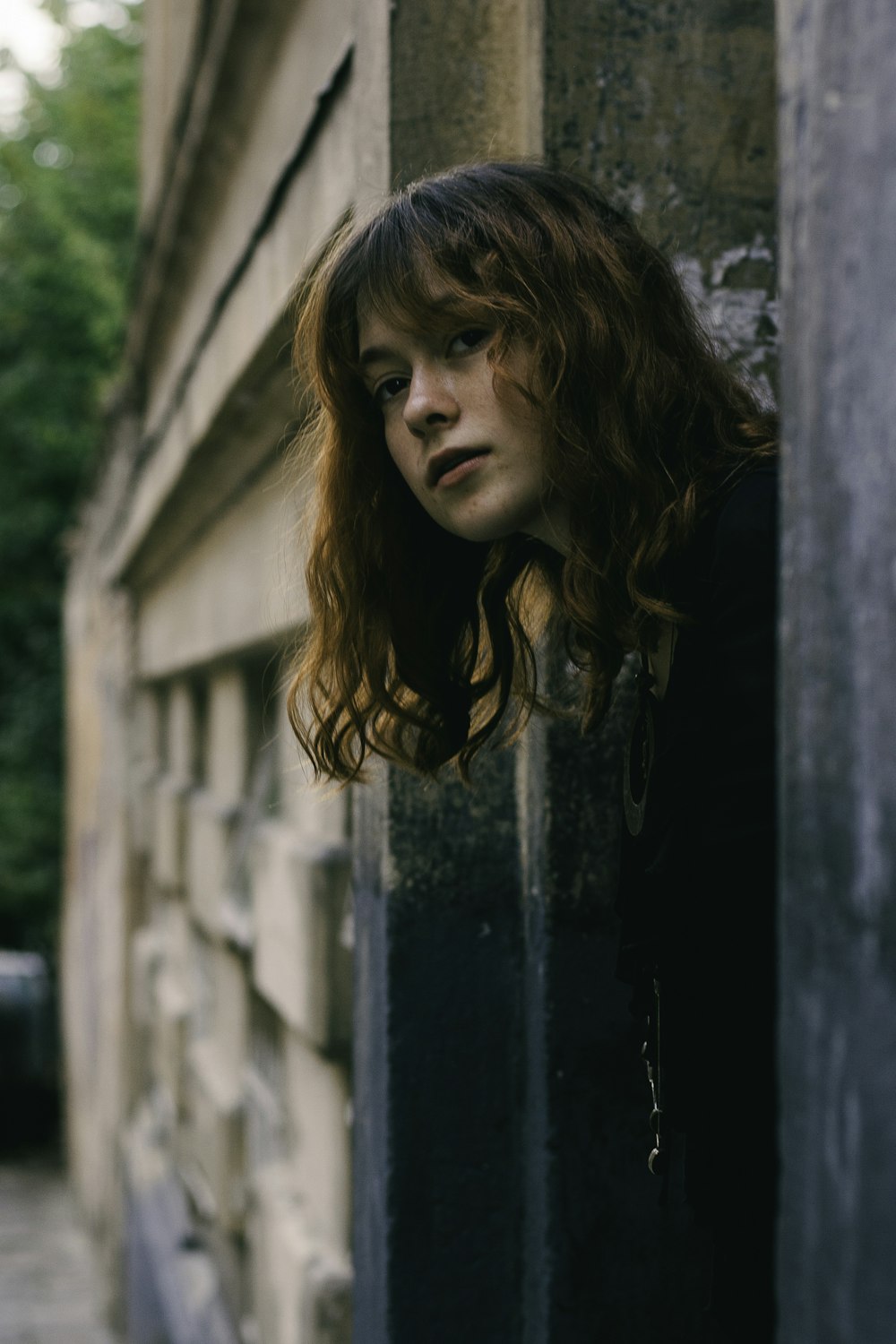 a woman with red hair leaning against a wall