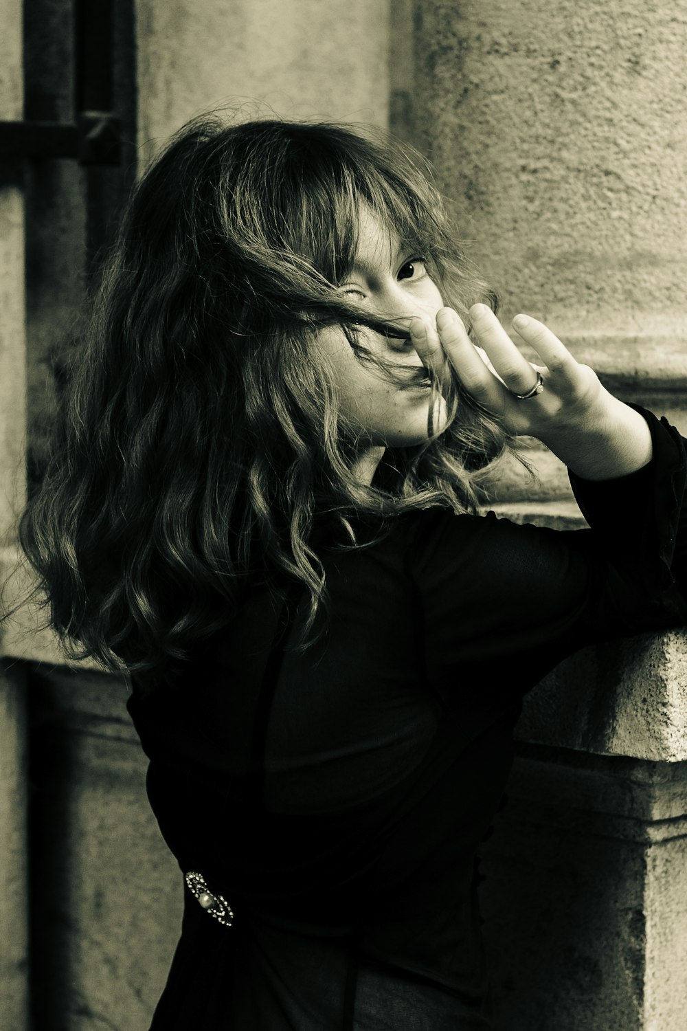 a woman leaning against a wall with her hands on her face